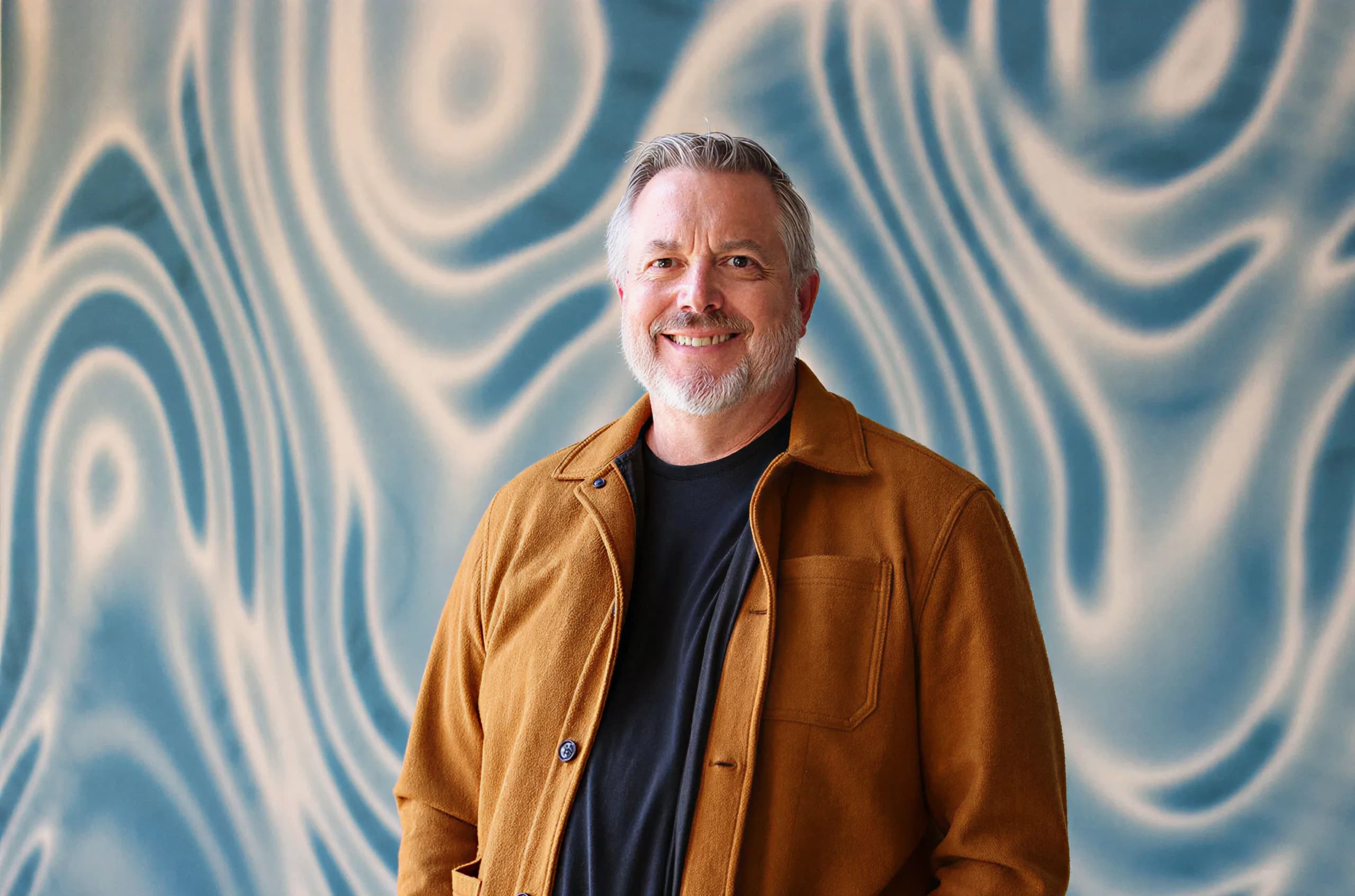 The Shipyard's David Sonderman smiles in front of an abstract background of water ripples