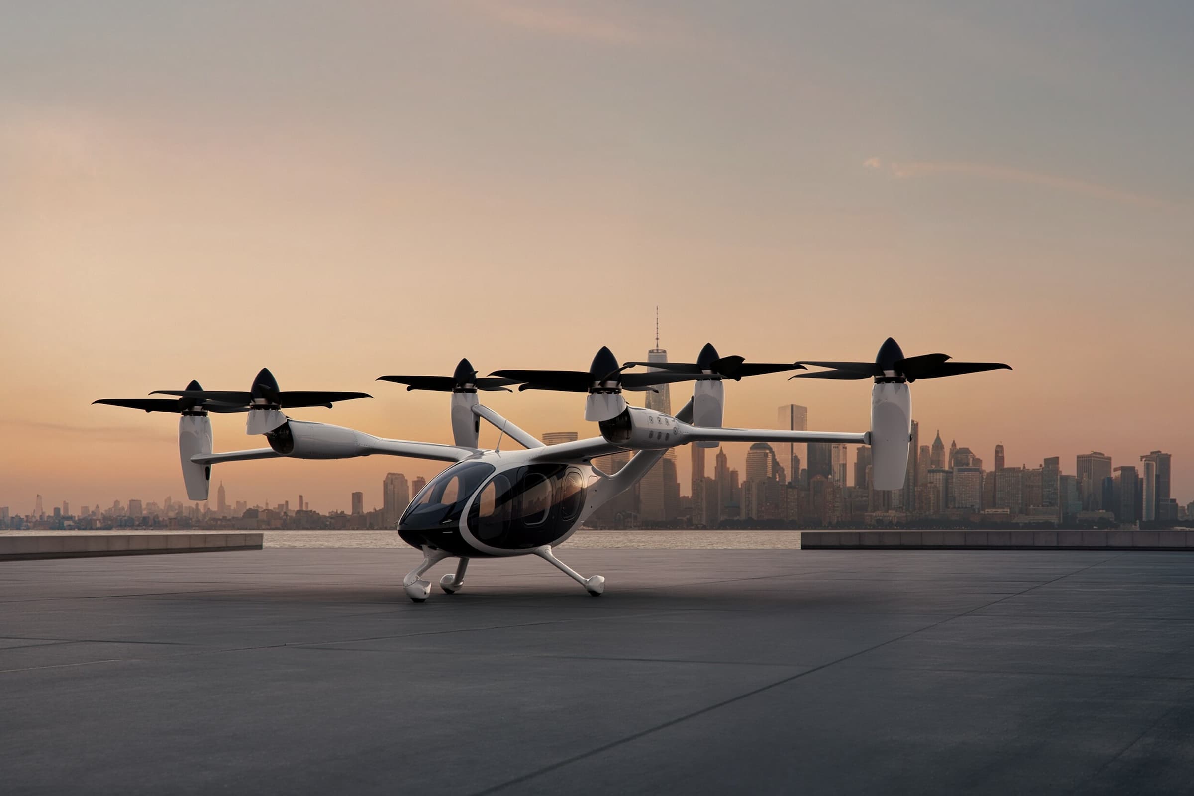 The Joby aircraft parked on a concrete platform with a cityscape in the background