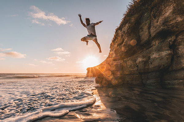 Person jumping from a cliff into the ocean