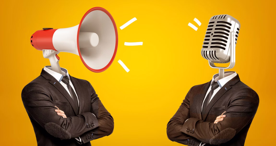 A mega phone wearing a suit talking into a microphone wearing a suit.