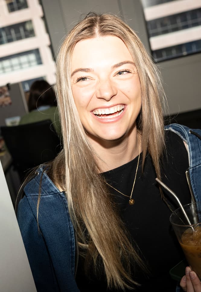 A blonde woman laughing and looking off to her right