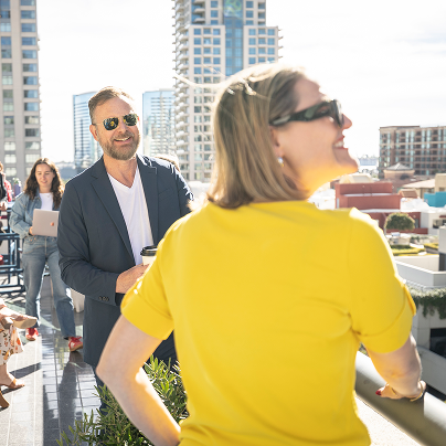 Two Shipyard employees in sunglasses standing outside on the outdoor deck at the San Diego office, enjoying the sun.