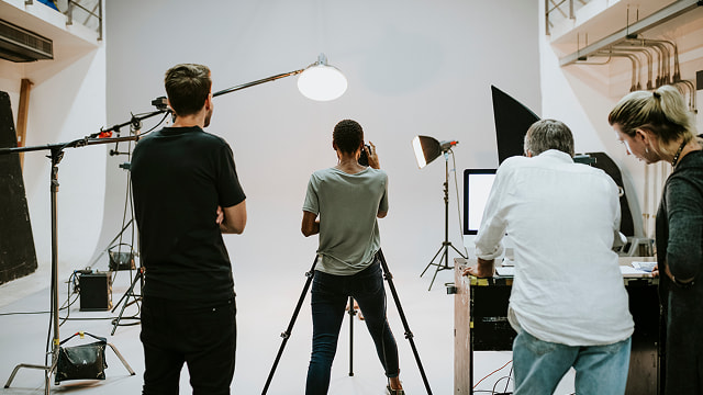 Several people working on a photo shoot taking place on a studio stage